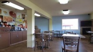 A dining area with tables and chairs, a trash bin, and a microwave. - Days Inn by Wyndham Champaign/Urbana (Champaign)