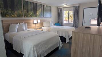 Habitación de hotel con dos camas, un escritorio, una silla, un cuadro y una ventana con cortinas.