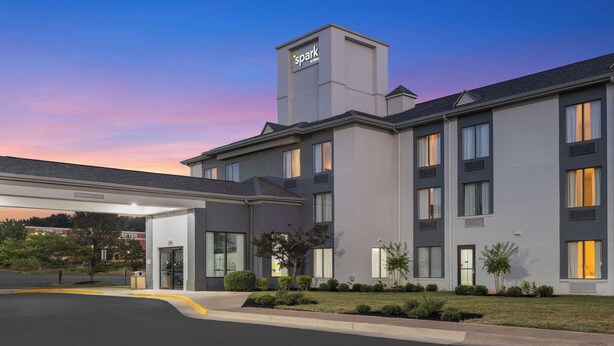 Um hotel moderno com entrada ampla, área de estacionamento e gramado bem cuidado.