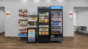 Uma área de venda automática com diversas opções de lanches e bebidas, incluindo micro-ondas e seções refrigeradas.