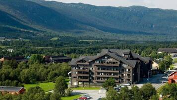 Un hôtel à plusieurs étages, doté d’un design moderne, situé dans une région montagneuse, entouré d’une végétation luxuriante et offrant une vue dégagée sur le paysage environnant.