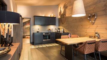 A modern kitchen with dark cabinets, a wooden dining table, and a heart-shaped decoration on the wall.
