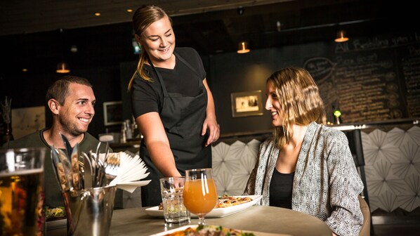 A restaurant setting with a waiter serving food to guests.