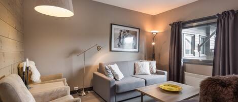 A modern living room with a sofa, armchairs, a coffee table, and a floor lamp.