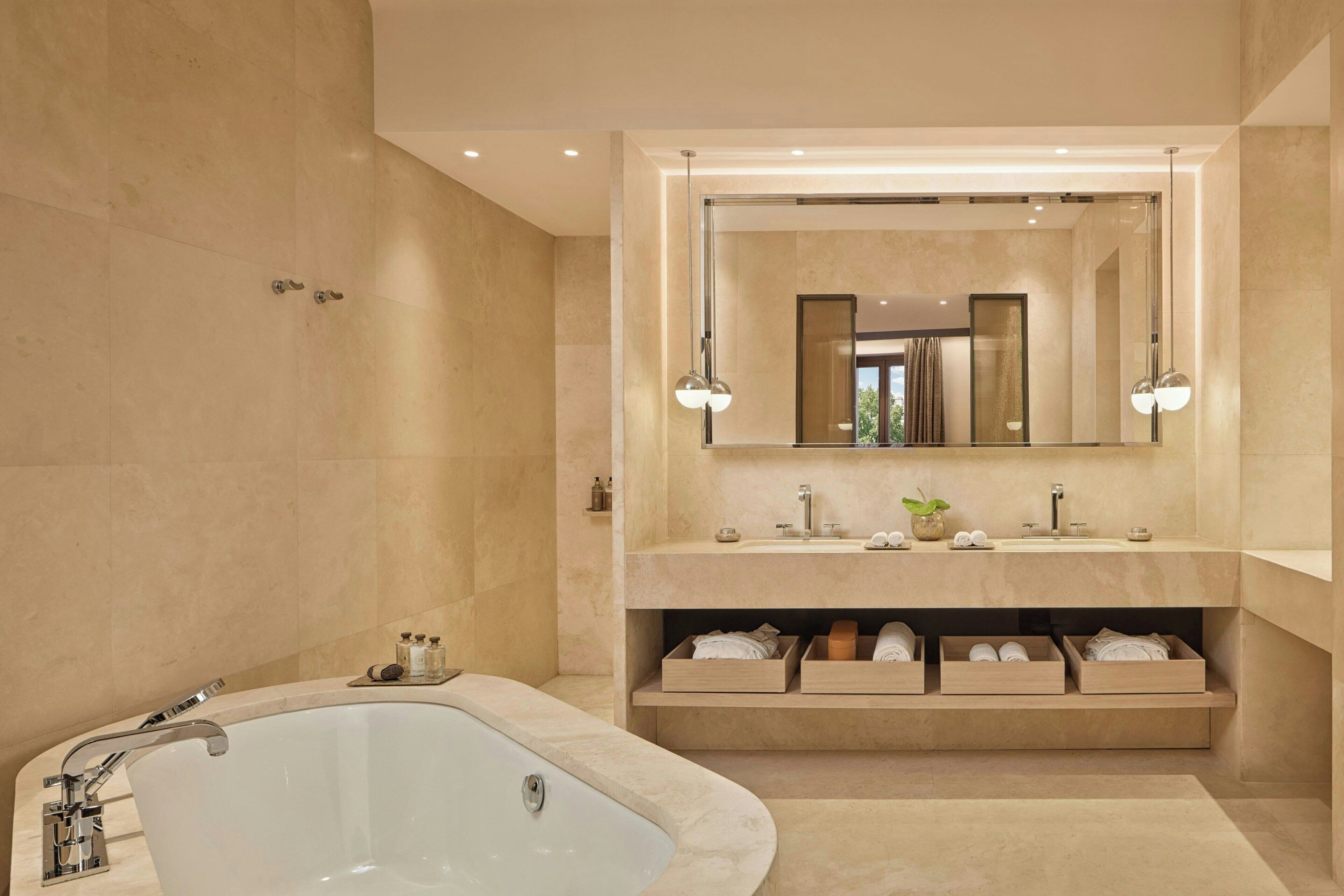 Un bagno moderno con una vasca freestanding, un grande specchio e scaffali a muro per gli articoli da toilette.