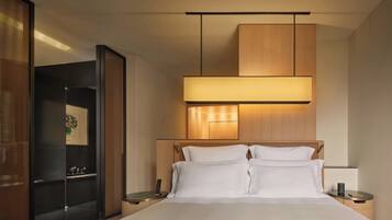 A modern hotel room with a large bed, bedside tables, a wooden headboard, and a mirror.