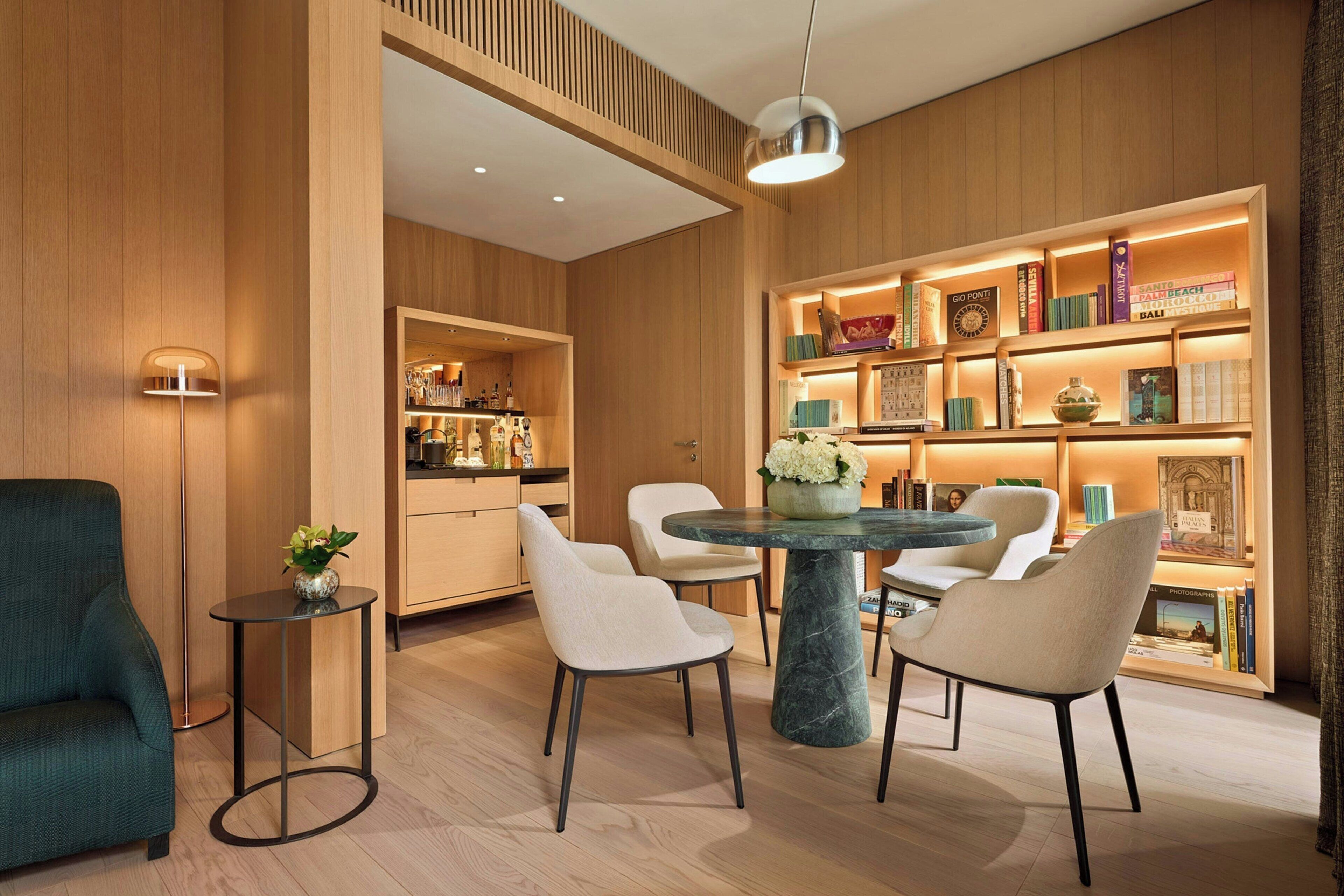 Zona pranzo moderna con un tavolo rotondo, quattro sedie e una libreria piena di libri e oggetti decorativi.