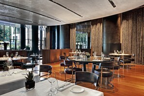 A spacious dining area with multiple tables and chairs, large windows, and a modern ceiling design. - Bvlgari Hotel Milano (Milan)