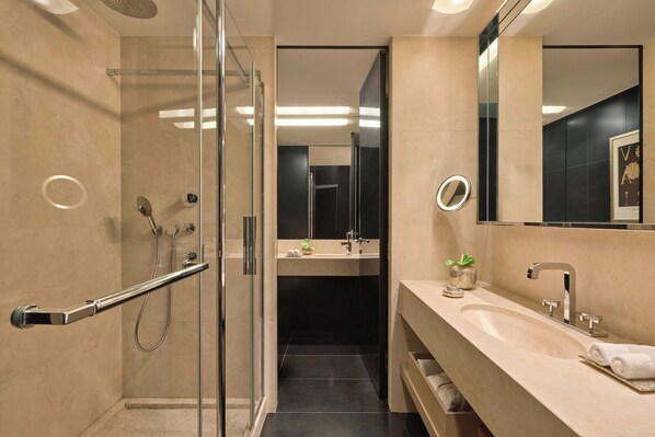 A modern bathroom with a glass shower enclosure, a vanity with a sink, and a large mirror.