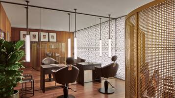 A modern salon with wooden floors, a reception desk, and three barber chairs.