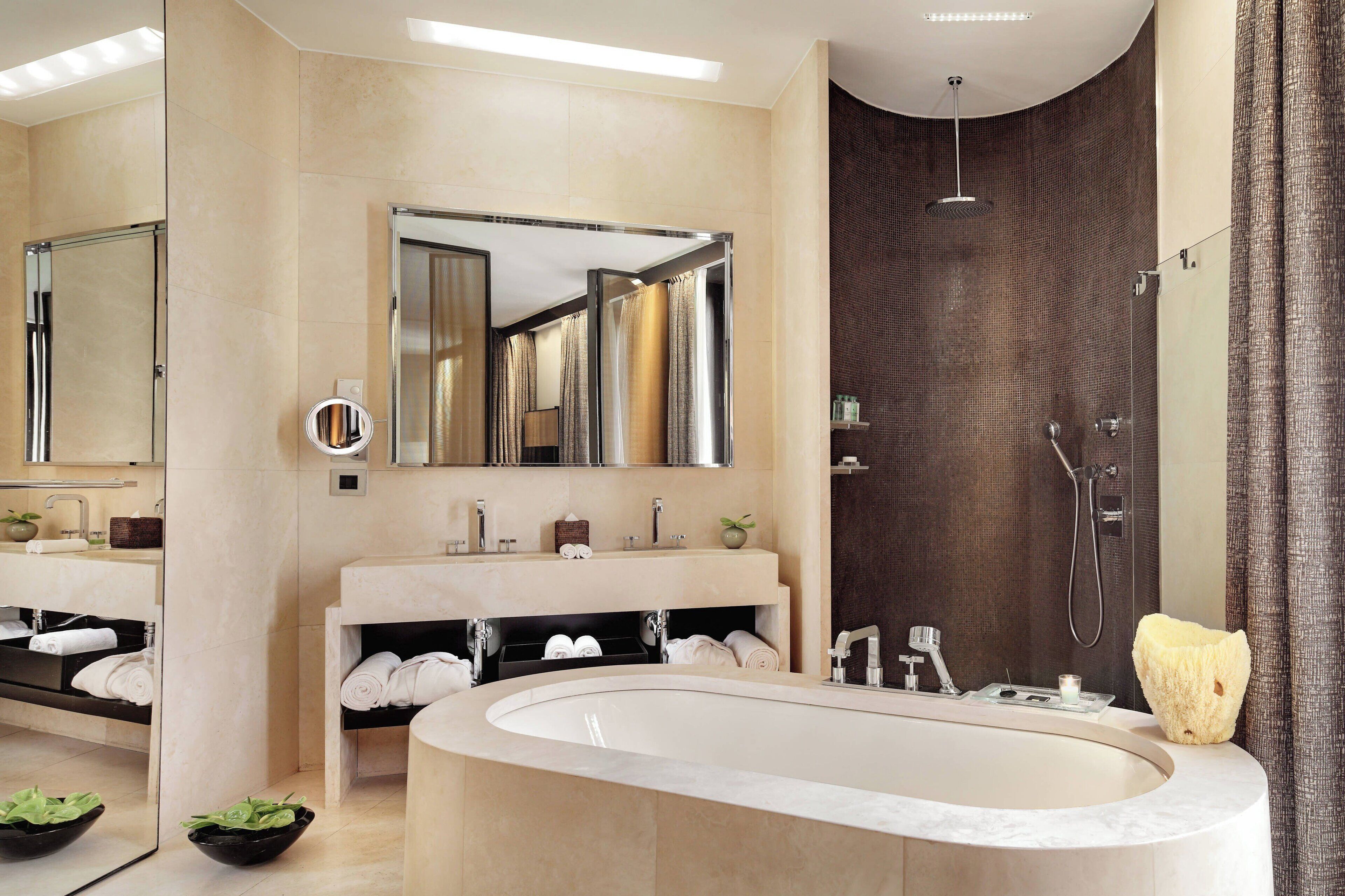 Een moderne badkamer met een ruim bad, twee wastafels, een spiegel en een douche.