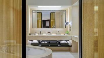 Een moderne badkamer met een grote spiegel, twee wasbakken, een badkuip en een wastafelmeubel met opbergladen.