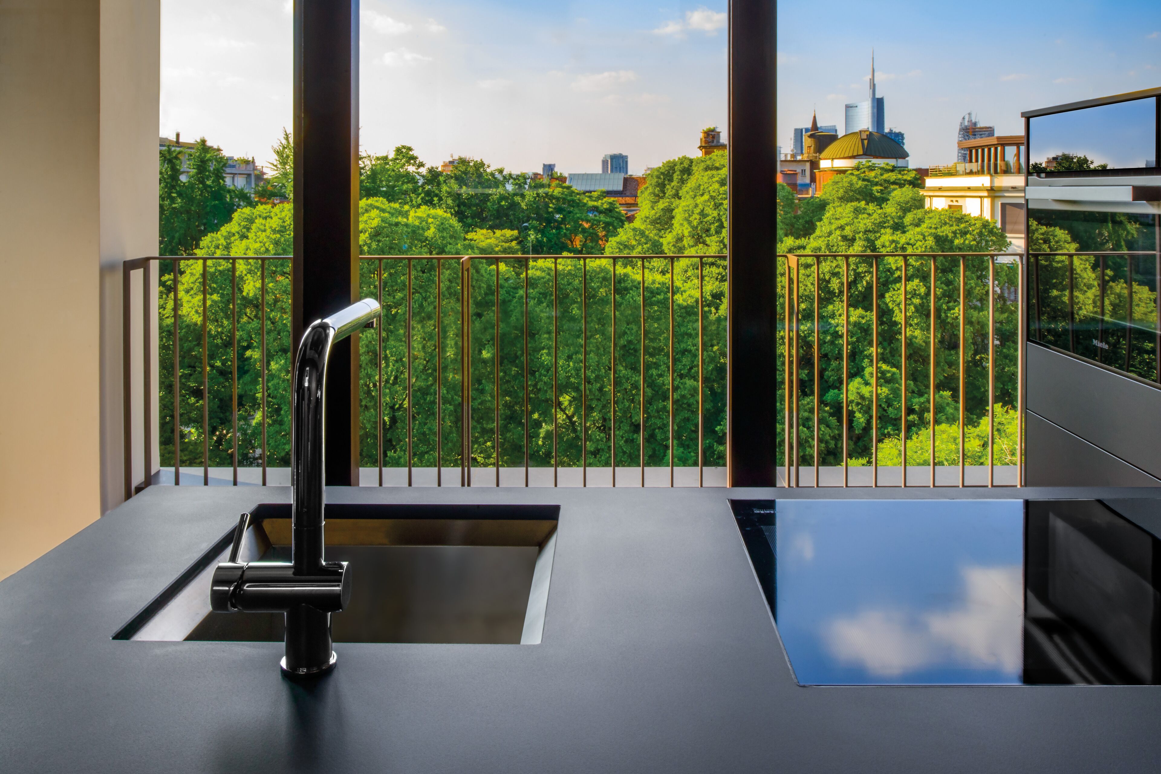A modern kitchen with a built-in sink and a view of a cityscape through large windows.