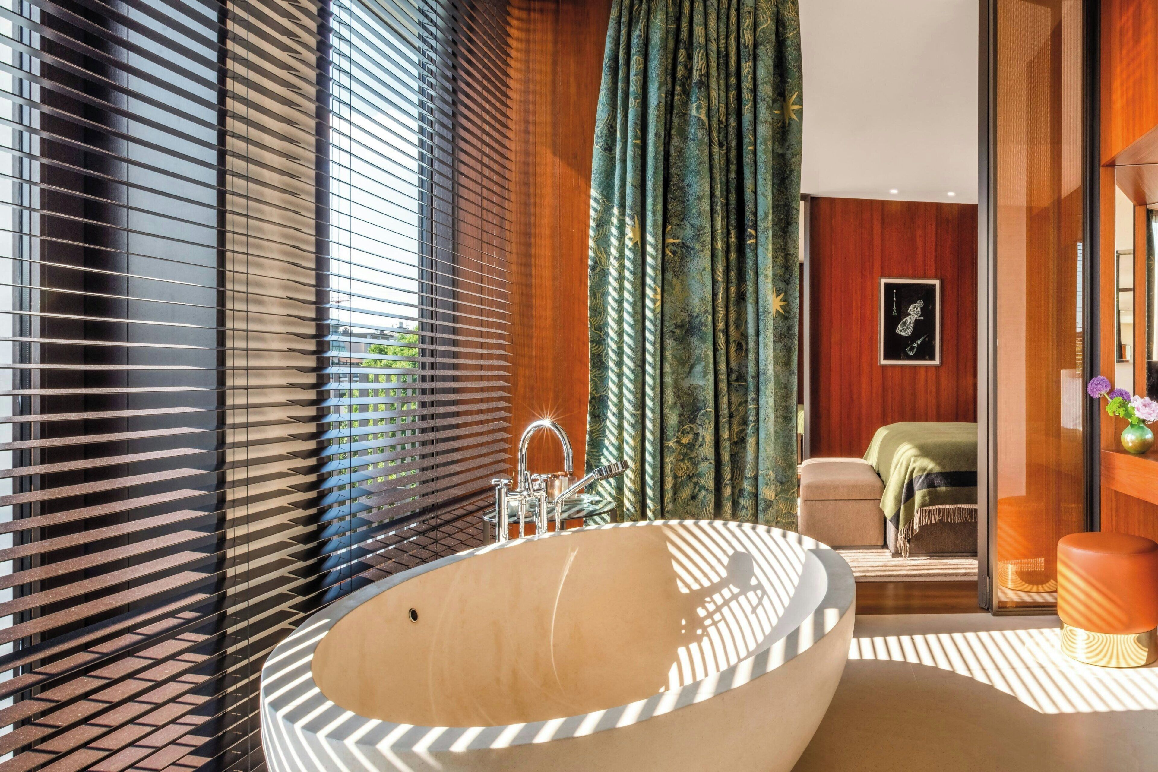 A modern bathroom with a freestanding bathtub, a shower area, and a view of the outdoors through large windows.