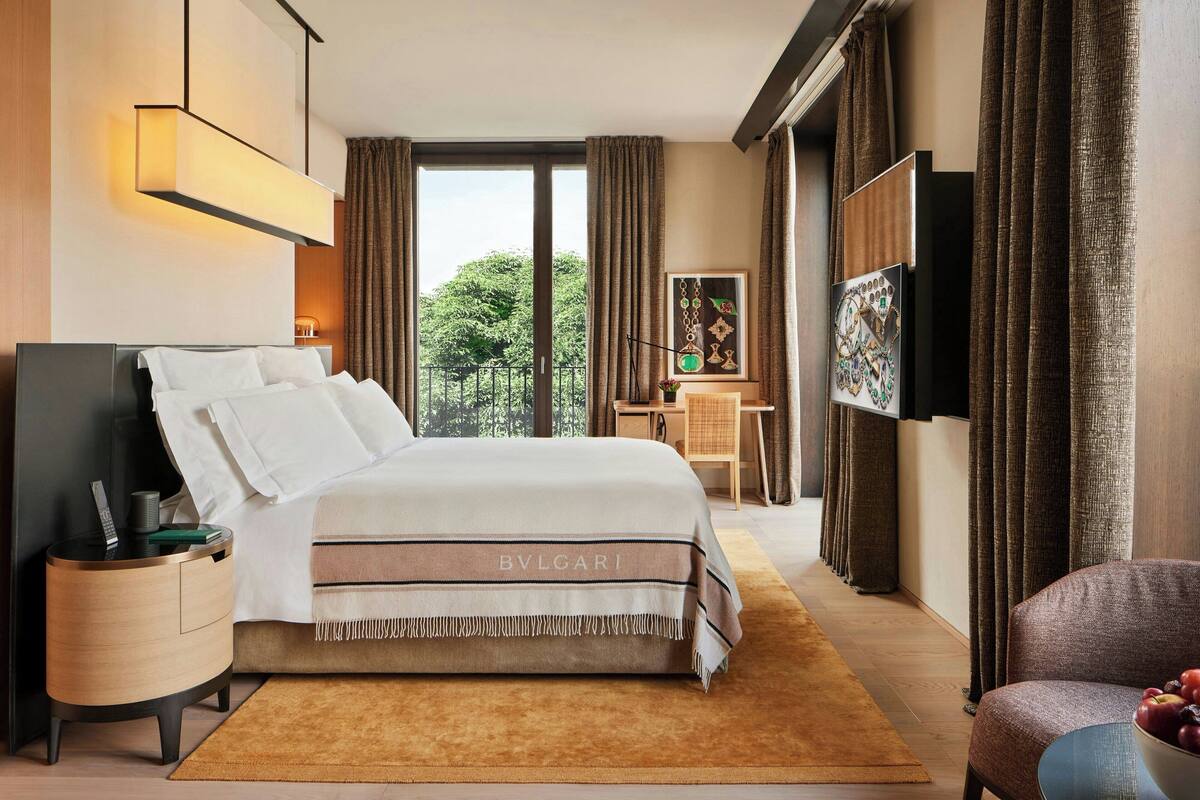 A hotel room with a large bed, a desk, a chair, and a TV.
