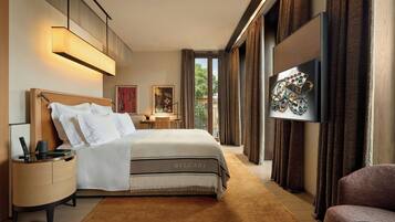 A modern hotel room with a large bed, a flat-screen TV, a nightstand, and a view of the outdoors.
