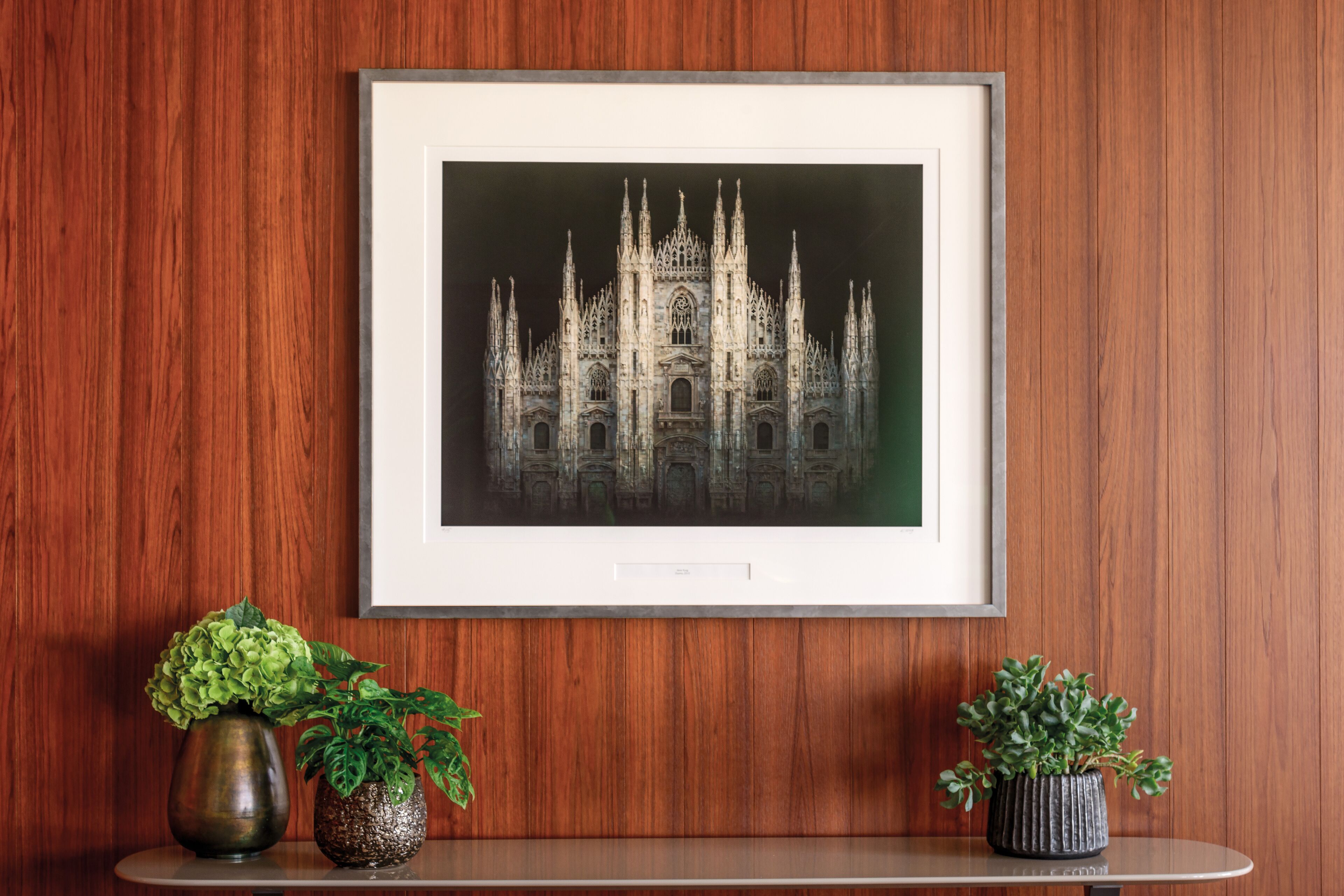 A framed architectural drawing of a Gothic-style building on a wooden wall.