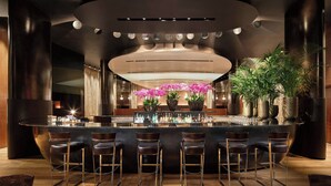 Un espace bar doté d’un îlot central, de tabourets de bar et de plantes en pot.