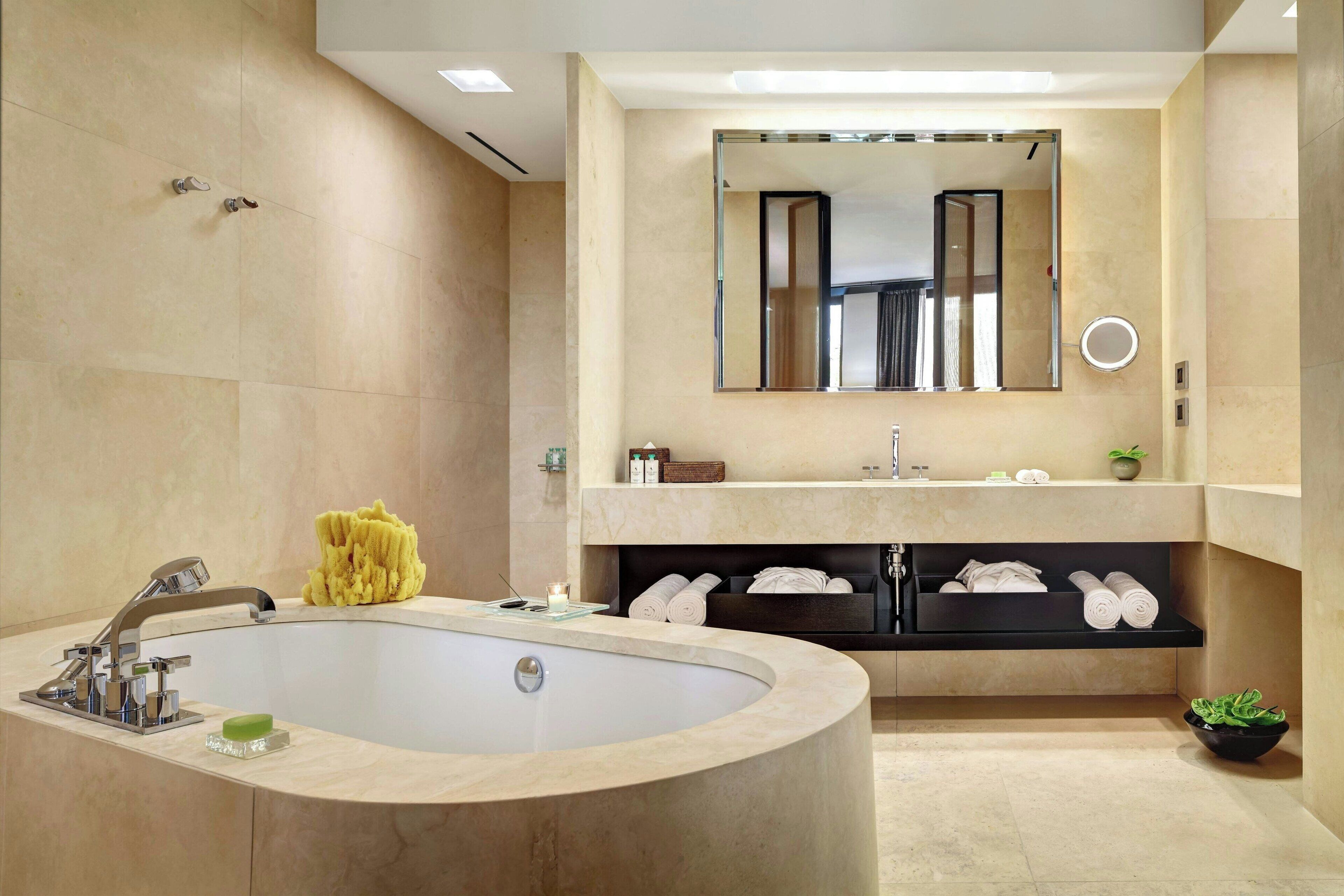 A modern bathroom with a freestanding bathtub, a large mirror, and a vanity with shelves for towels and toiletries.