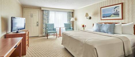 A hotel room with a bed, a desk, a television, a chair, and a lamp.