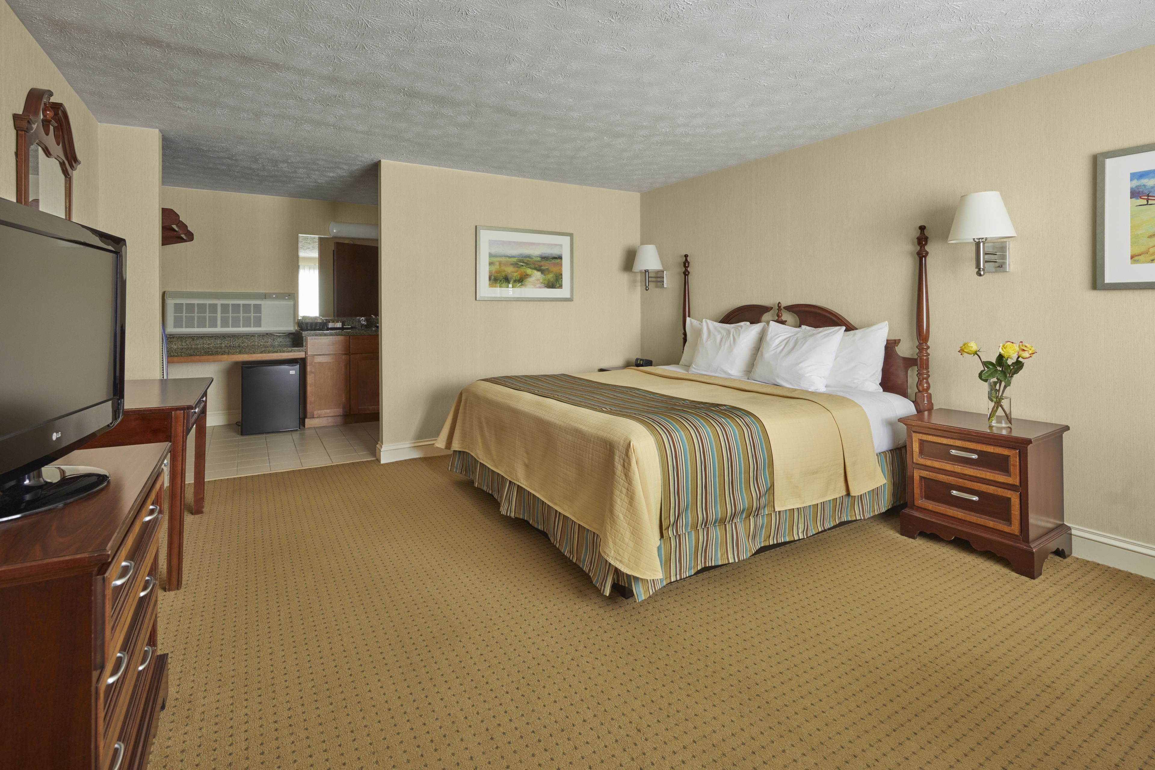 A hotel room with a bed, bedside table, lamp, and a television.