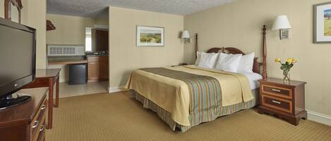 A hotel room with a bed, bedside table, lamp, and a television.