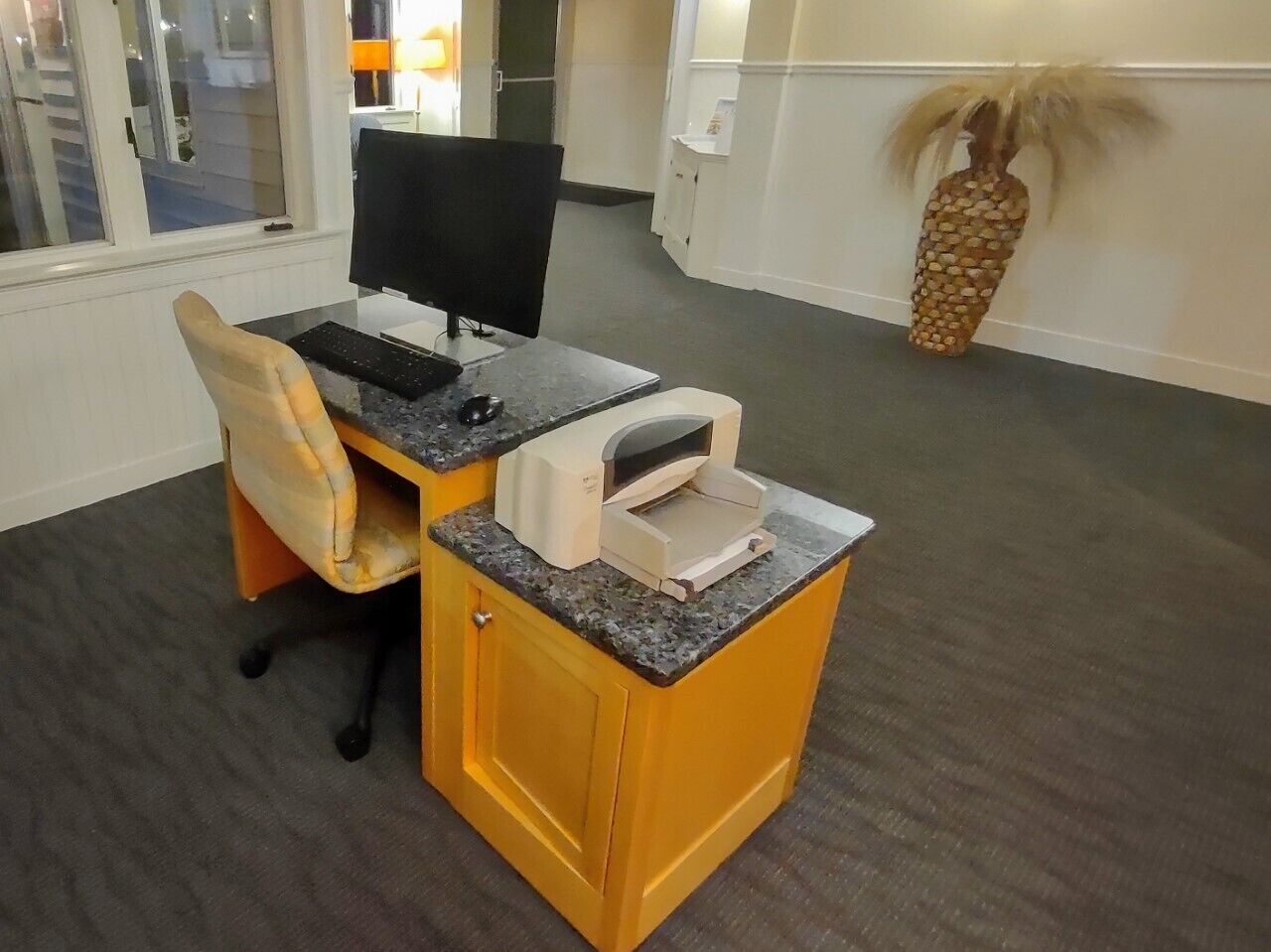 Um espaço de escritório compacto, com uma mesa, cadeira e impressora.