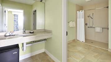 A bathroom with a sink, mirror, towel rack, shower, and toilet.
