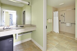 A bathroom with a sink, mirror, towel rack, shower, and toilet.