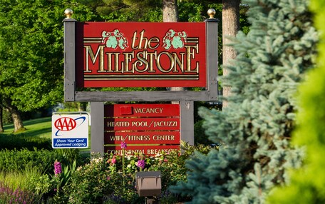 A sign for 'The Milestone' with amenities including a heated pool, Jacuzzi, WiFi, fitness center, and continental breakfast.