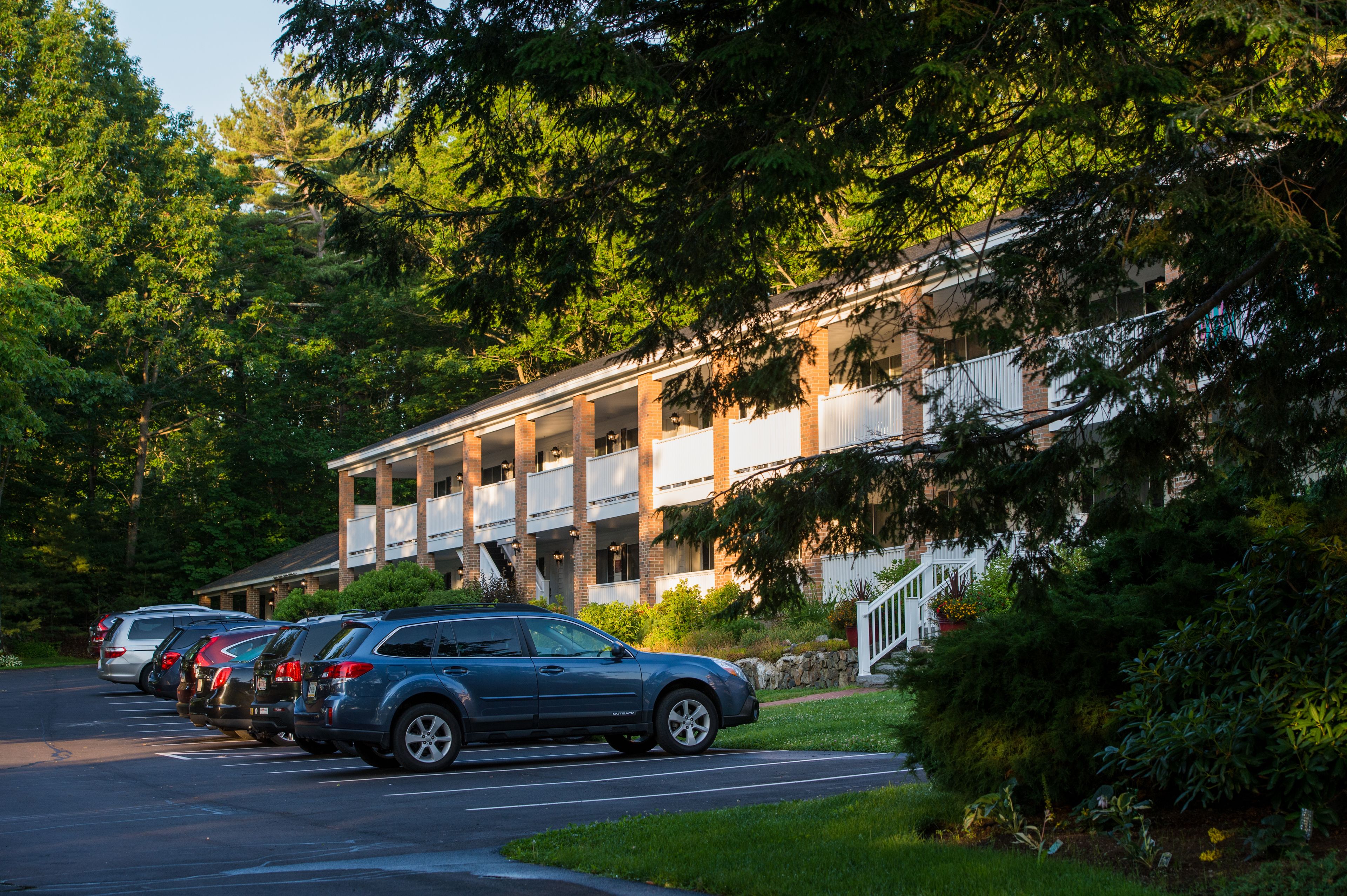 A building with a brick facade, multiple windows, and a parking lot with several cars.