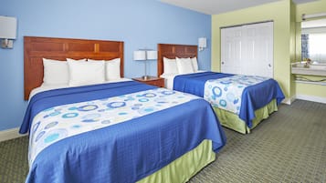 A hotel room with two beds, each with a wooden headboard, a nightstand, and a lamp.