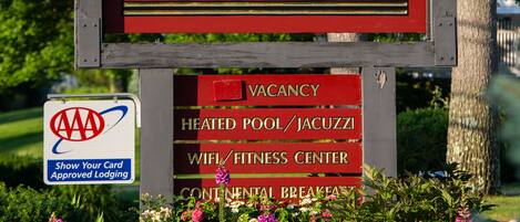 A sign for 'The Milestone' with amenities including a heated pool, jacuzzi, WiFi, fitness center, and continental breakfast.