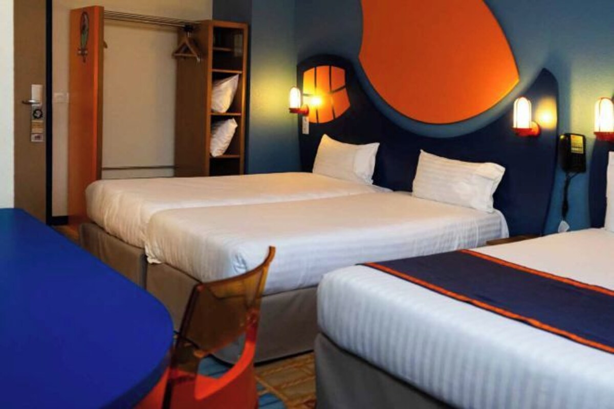 Una habitación de hotel con dos camas, un armario, una silla y una mesa.