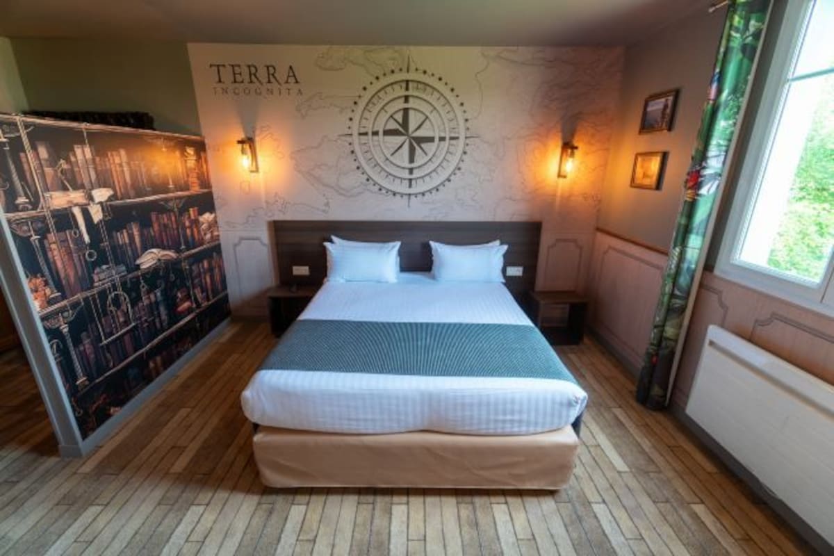 Un dormitorio ordenado con una cama grande, un mapa mural y una estantería.