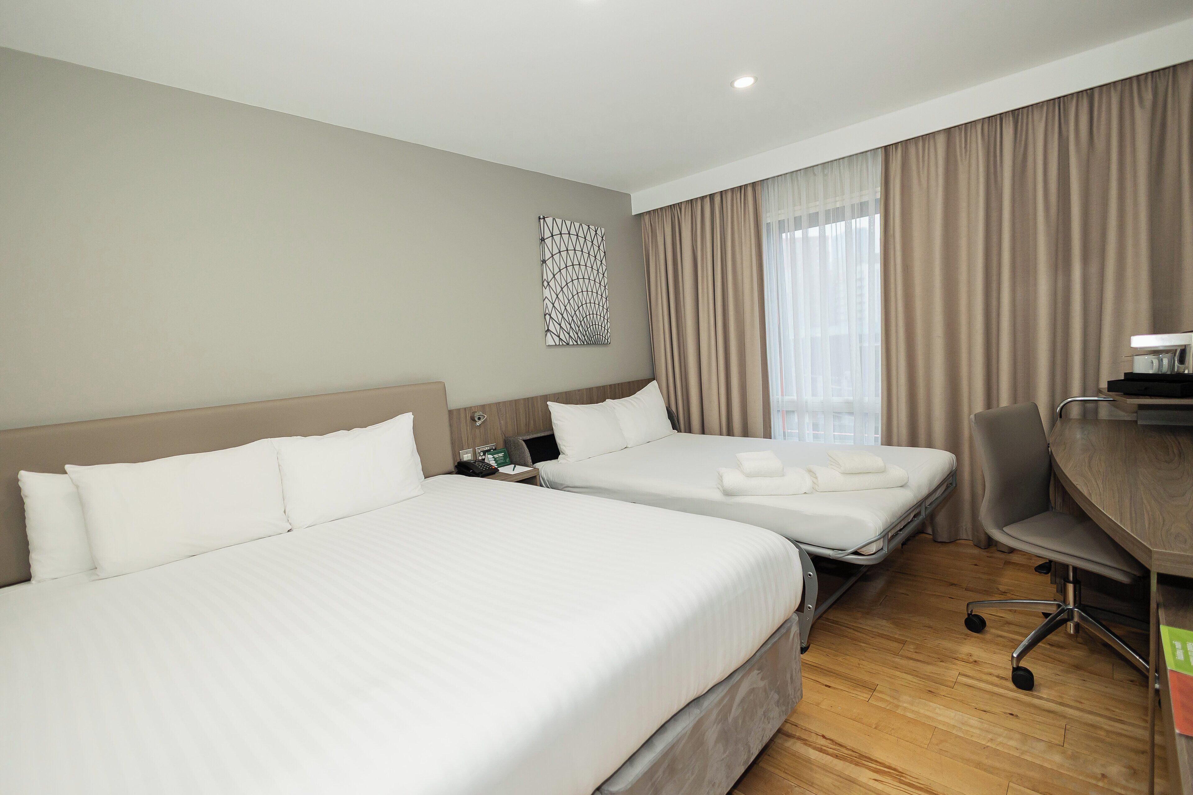 Une chambre d’hôtel avec deux lits, un bureau et une chaise.