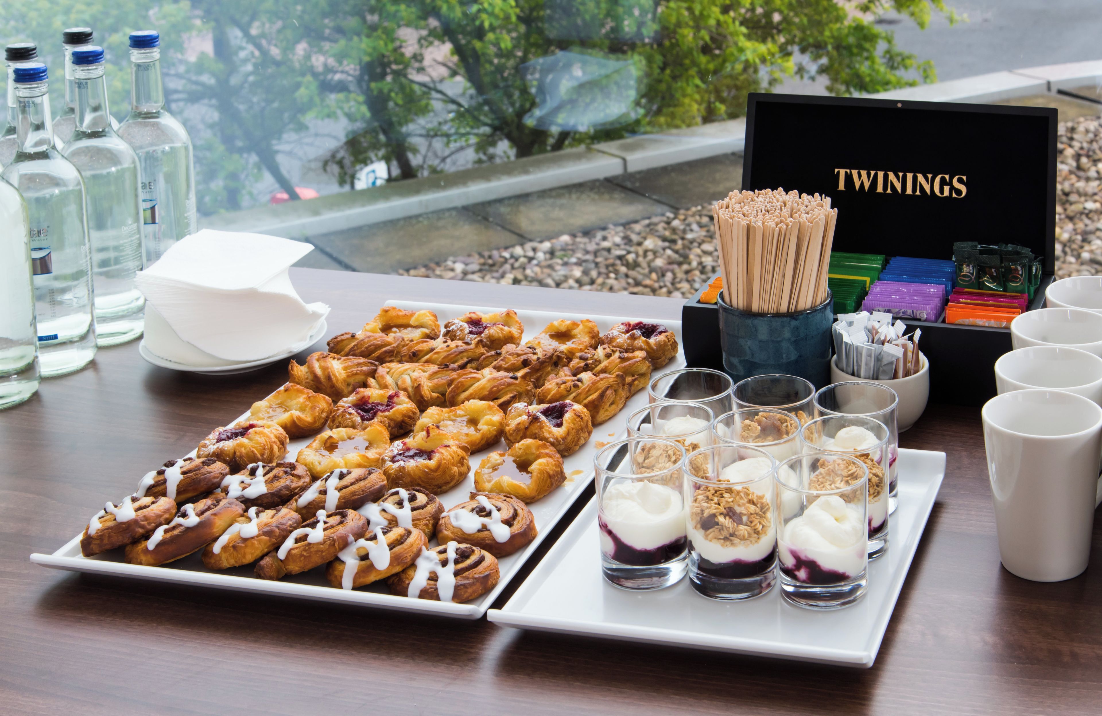 A table with pastries, glasses of yogurt parfait, and Twinings tea boxes.