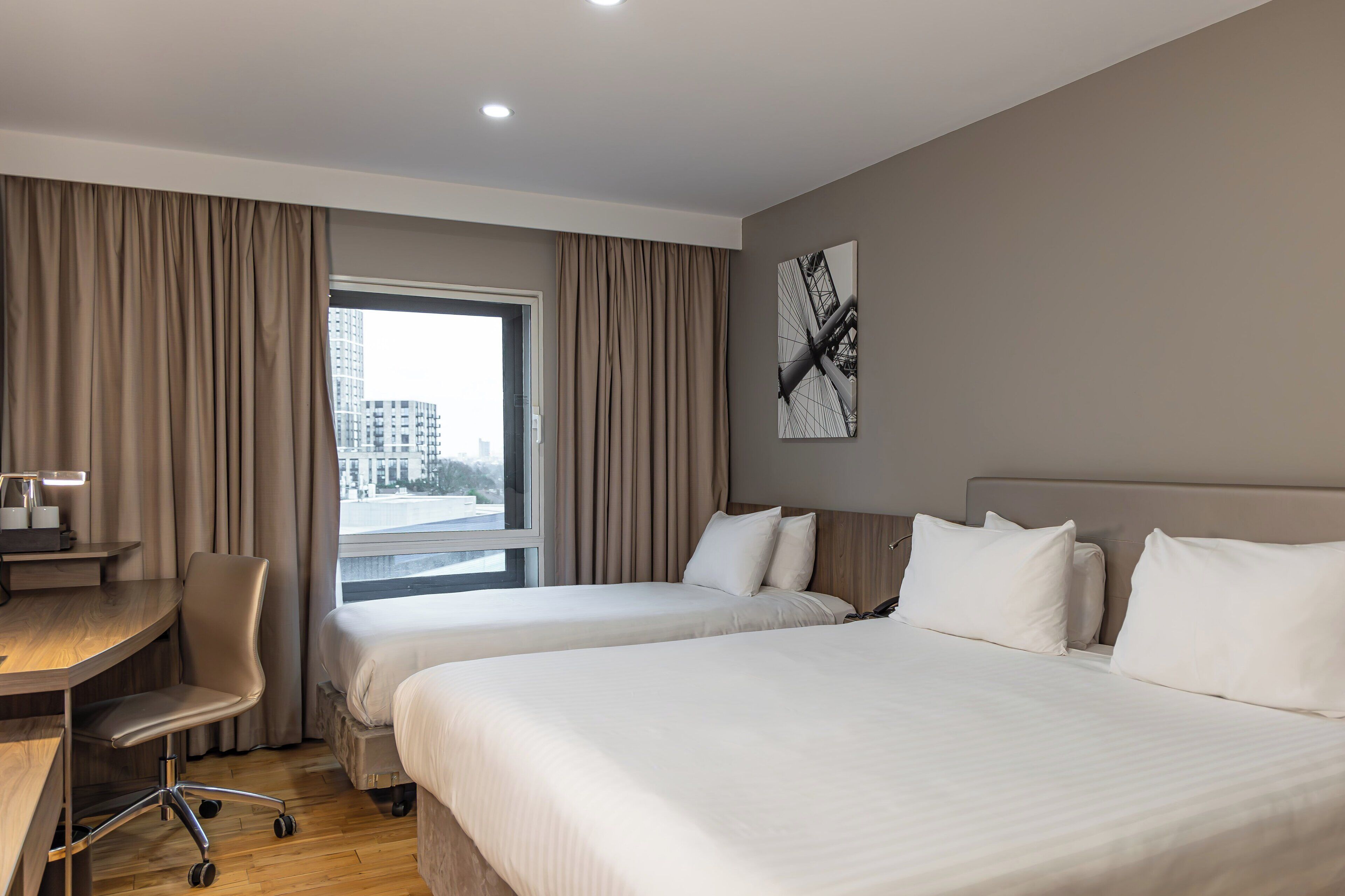 A hotel room with two beds, a desk, and a chair.