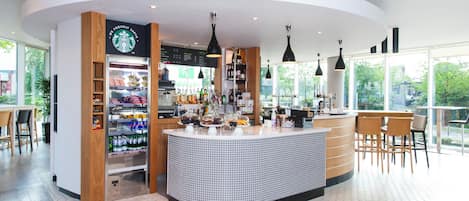 A modern coffee shop with a central counter, a Starbucks sign, and a menu board.