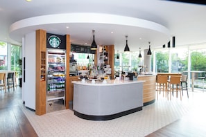 A modern coffee shop with a central counter, a Starbucks sign, and a menu board. - Holiday Inn London - West by IHG (London)