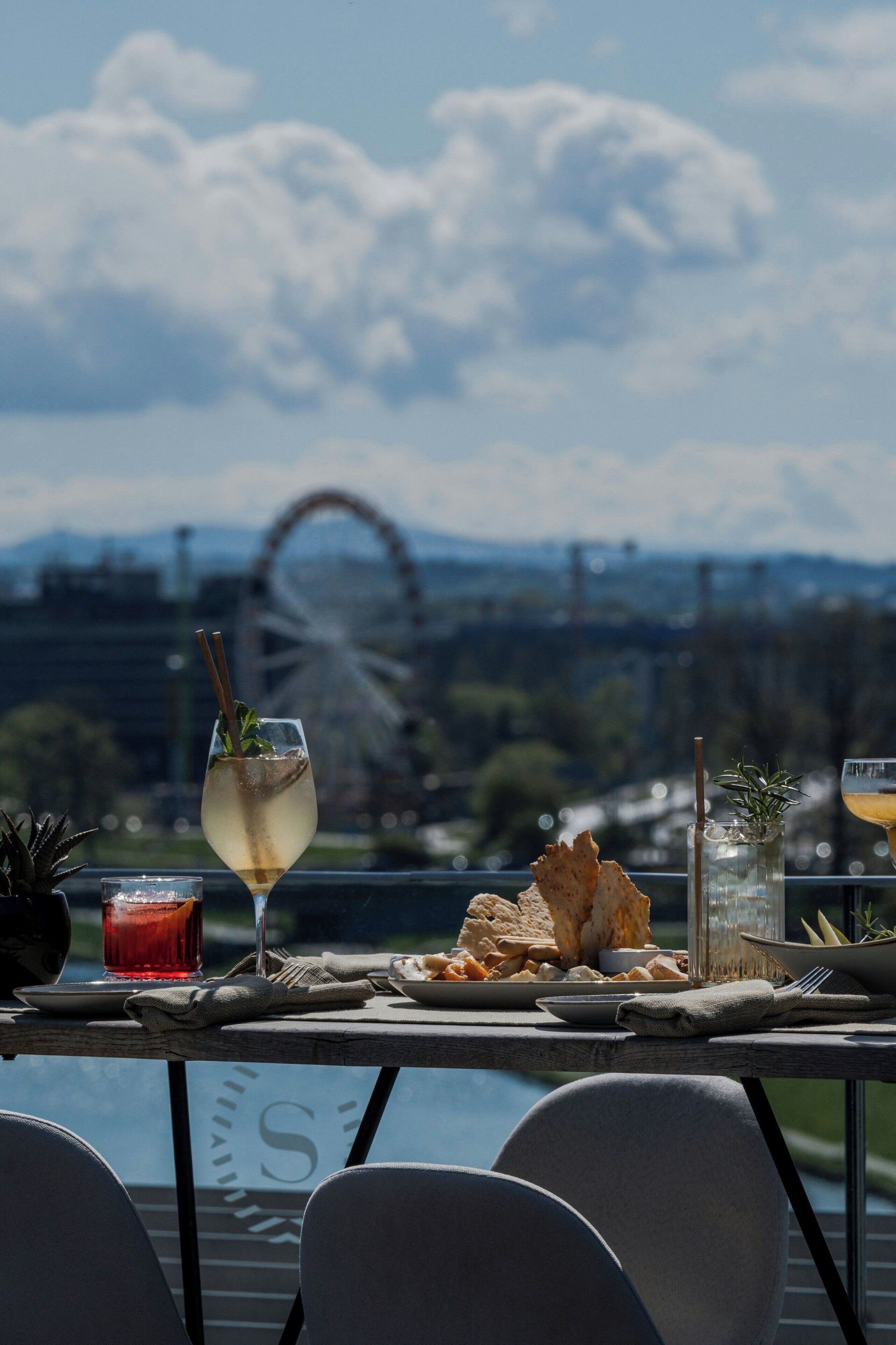 A table with a drink, snacks, and a view of a Ferris wheel.