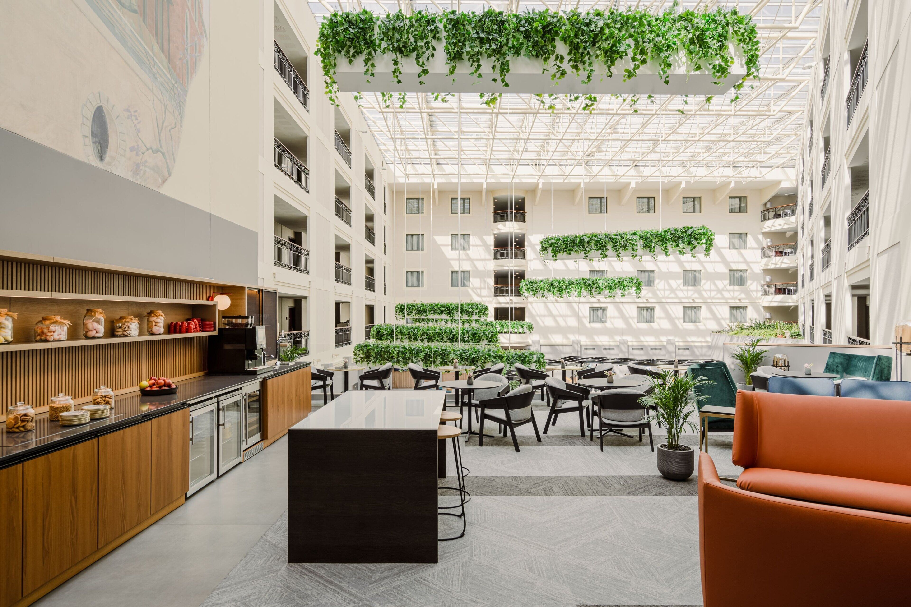 A modern atrium with a central seating area, high ceilings, and greenery.