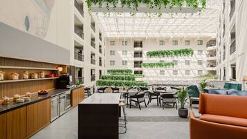 A modern atrium with a central seating area, high ceilings, and greenery.