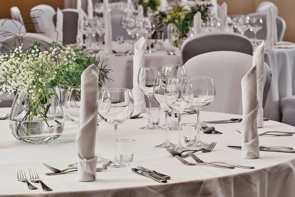 A formal dining table set with white tablecloths, clear glassware, and white napkins. - Sheraton Grand Krakow (Kraków)