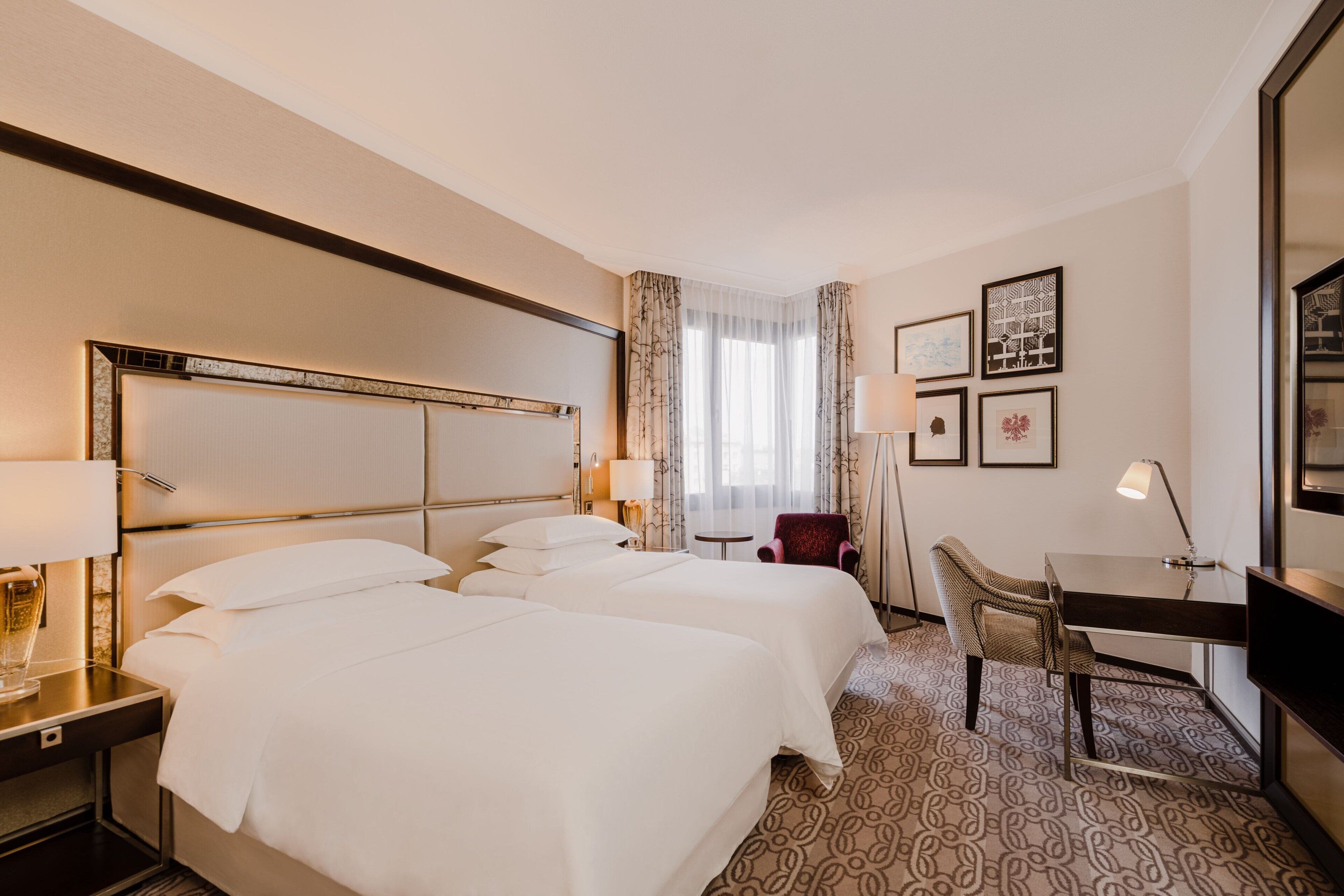 Ett hotellrum med två sängar, ett skrivbord, en stol och en TV.