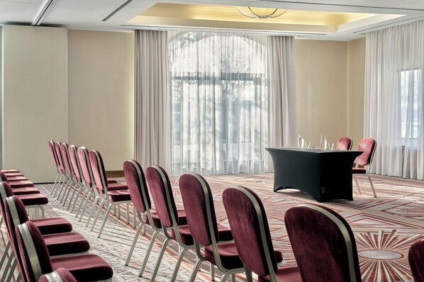 A conference room with rows of chairs, a table, and large windows with curtains. - Sheraton Grand Krakow (Kraków)