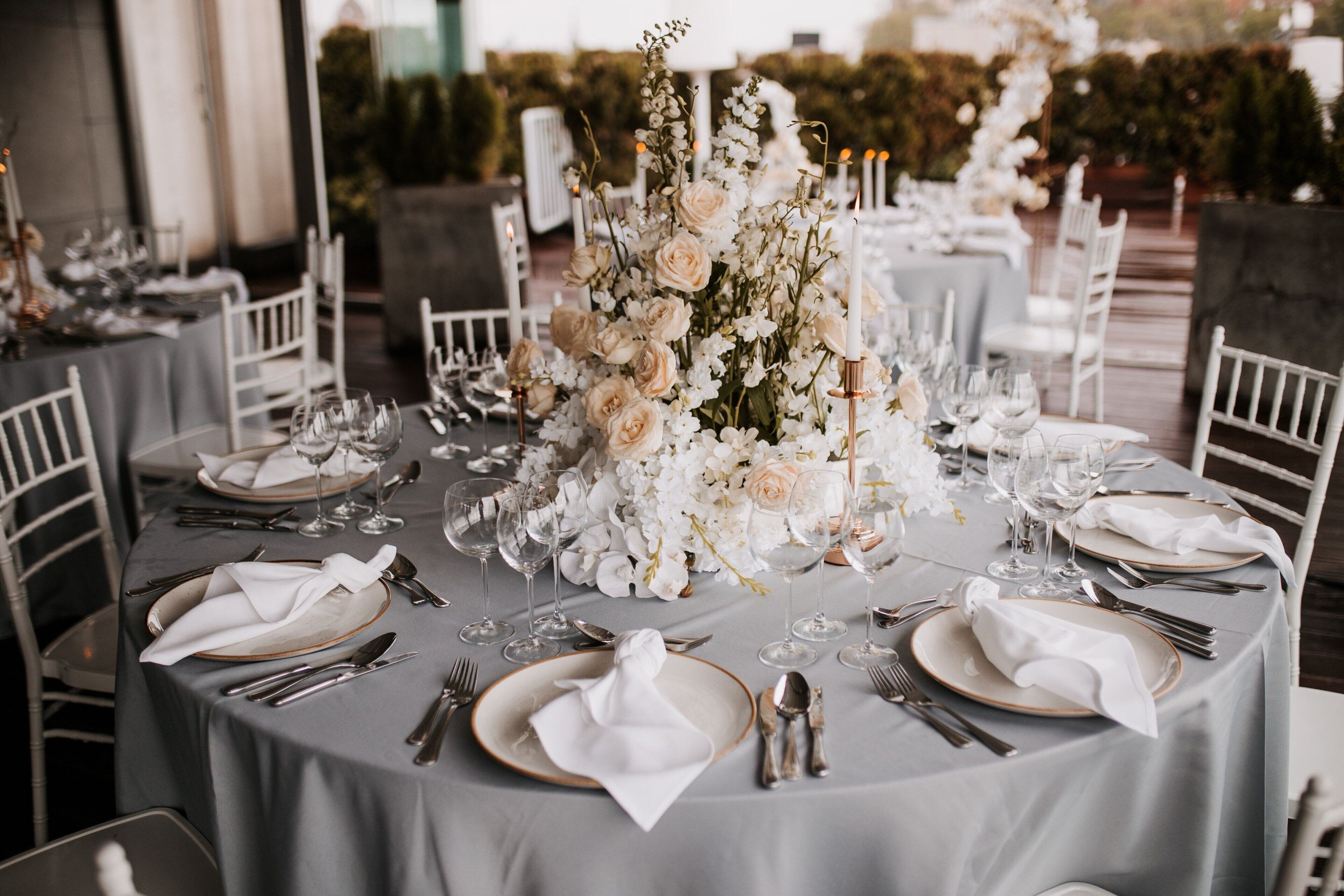A round table set for a formal event with white flowers and candles.