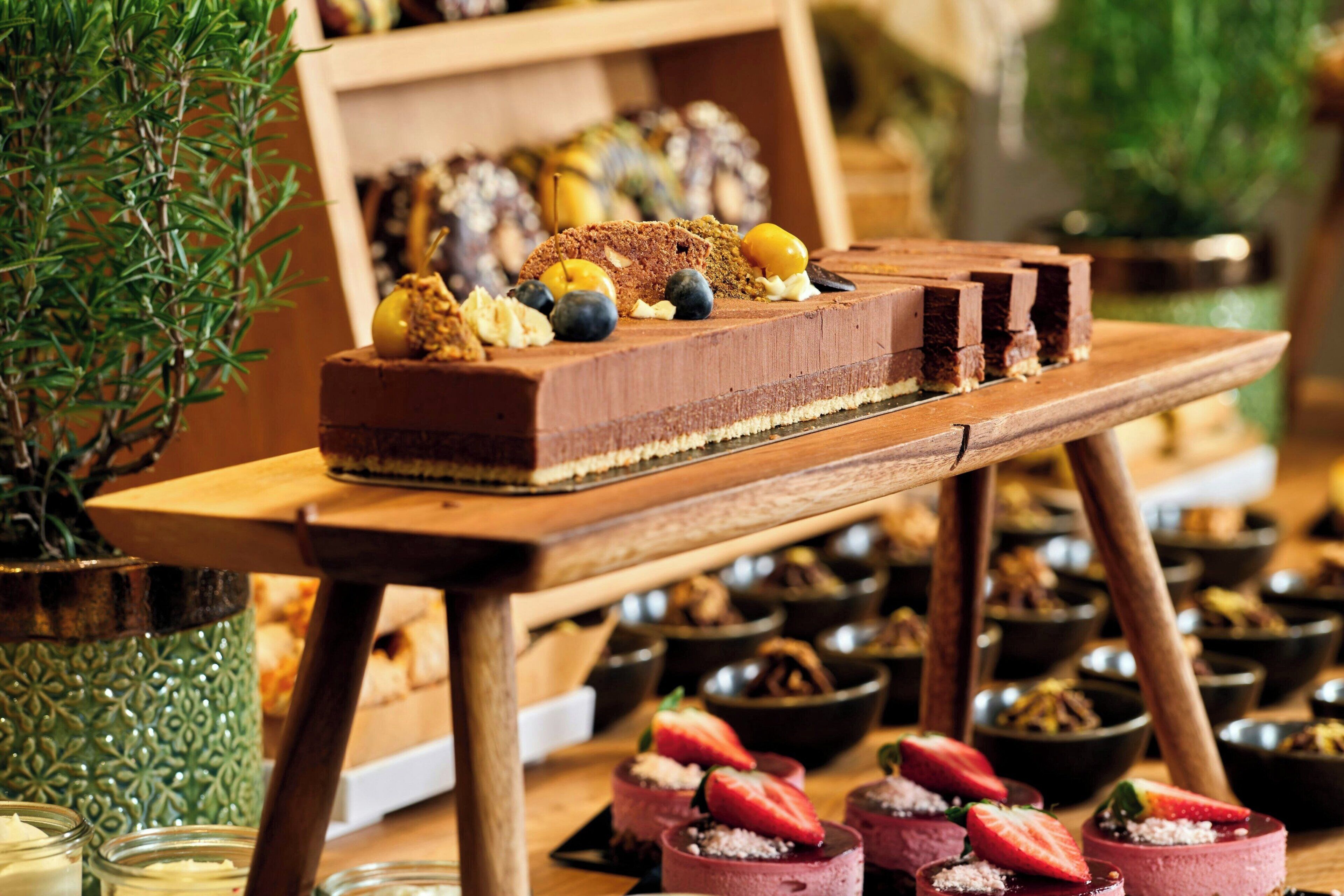 A dessert table with various sweets and a chocolate cake.