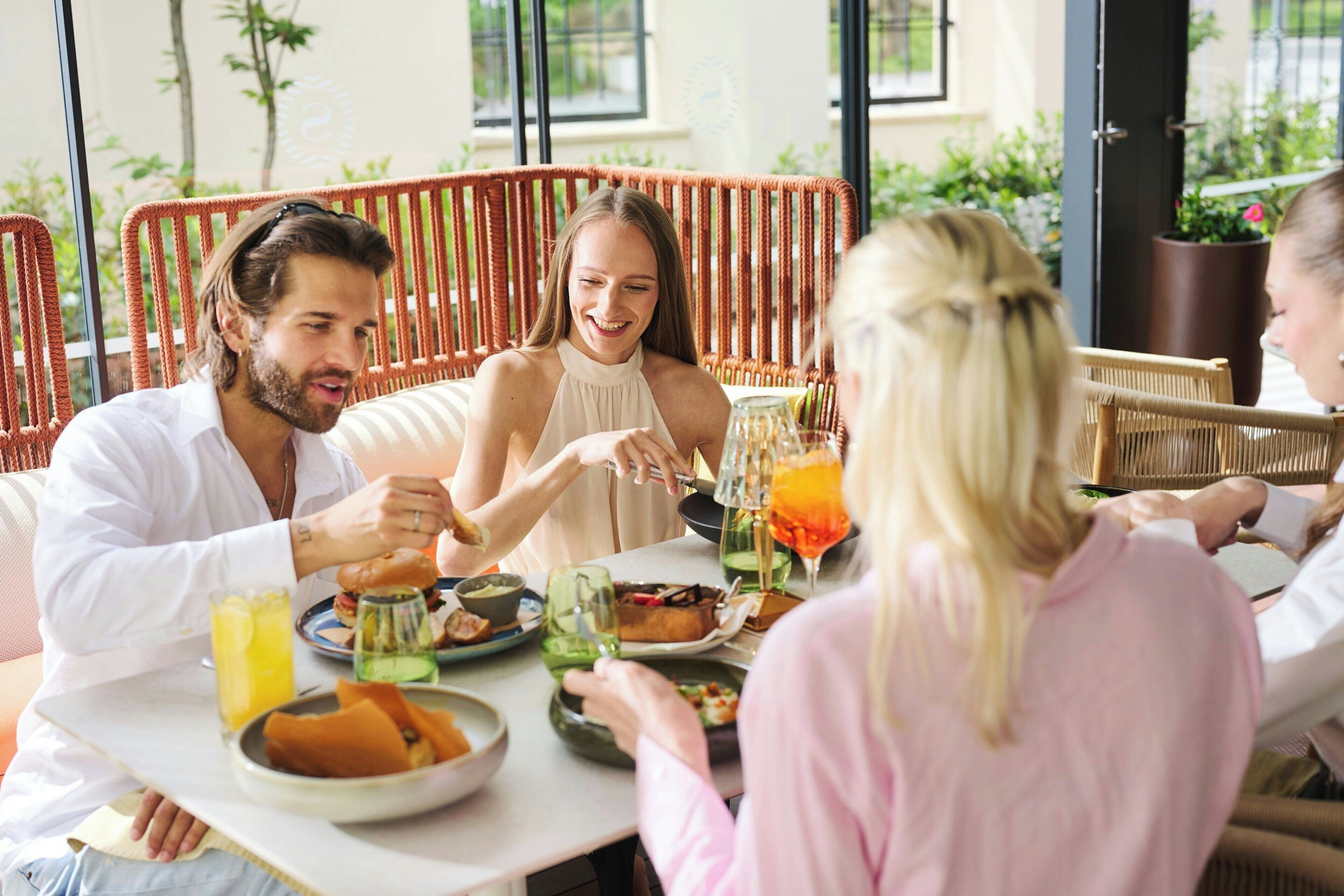 Un grupo de personas cenando en una mesa con distintos platos y bebidas.