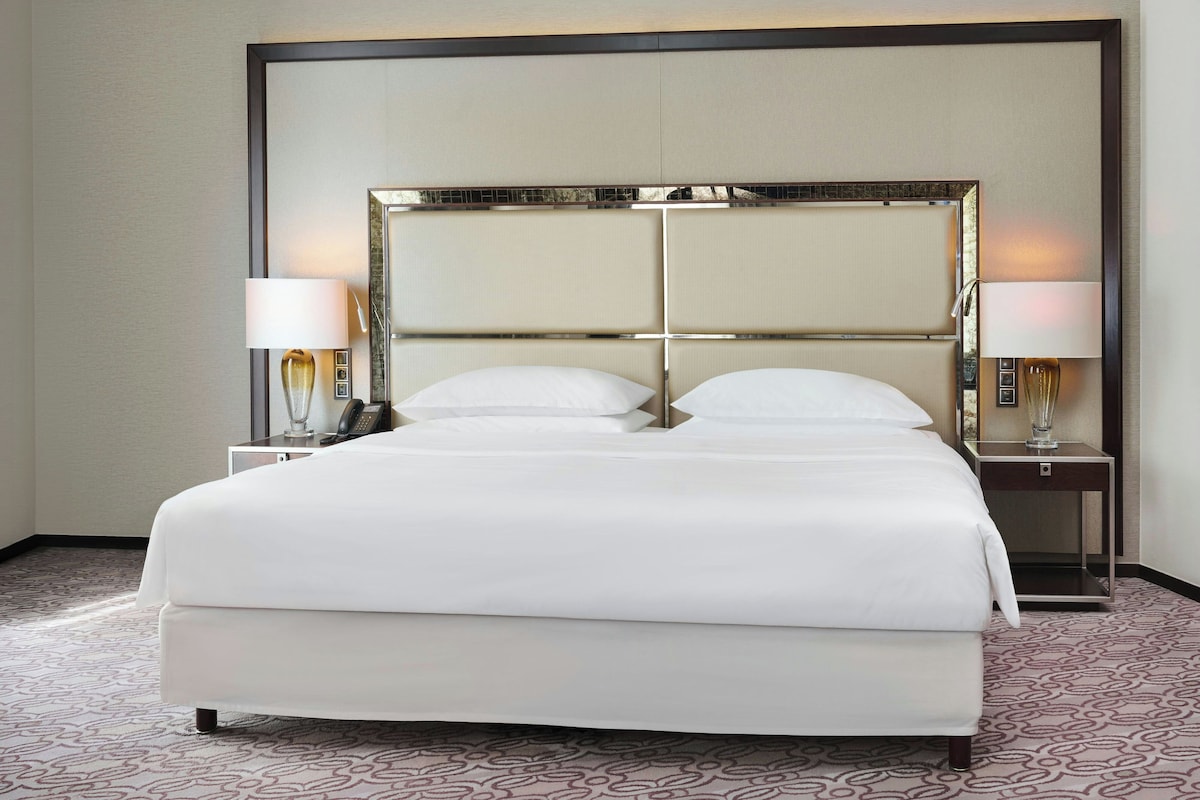 Una habitación de hotel con una cama grande, dos mesitas de noche y un espejo sobre la cama.